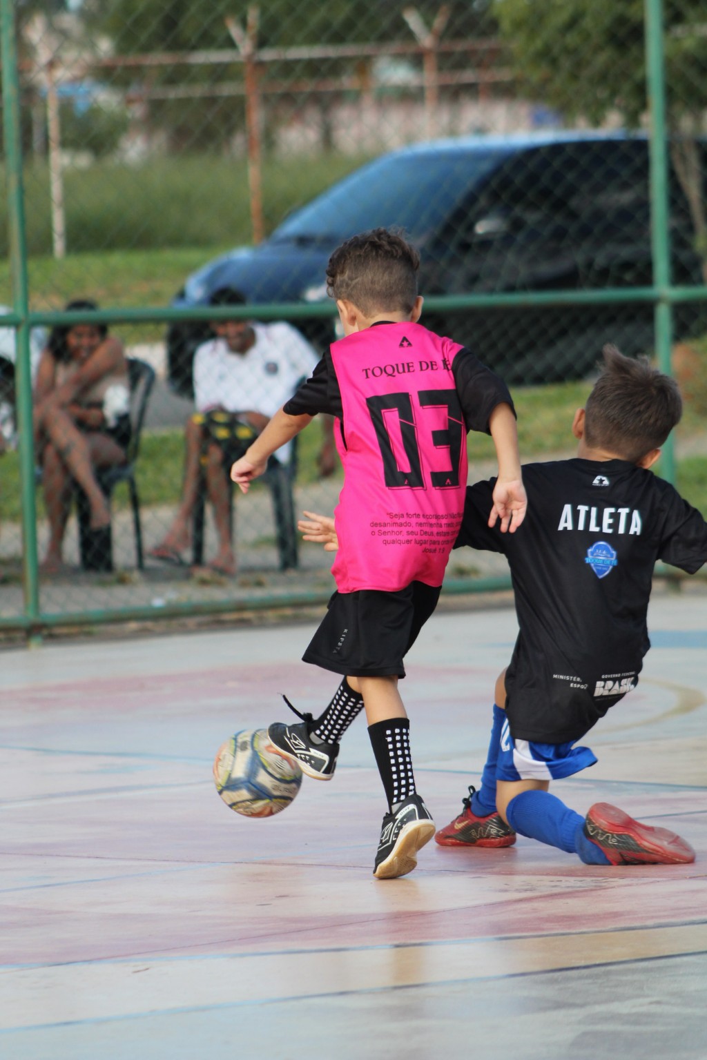 Duas crianças participando de uma atividade de futsal na quadra
